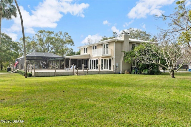 back of property with a balcony, a lanai, and a yard