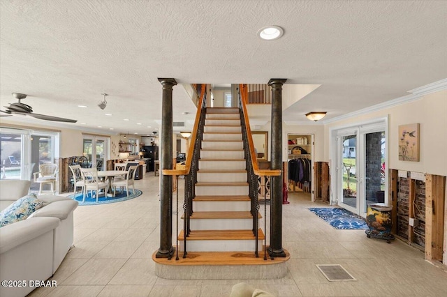 staircase with decorative columns, crown molding, a healthy amount of sunlight, and ceiling fan