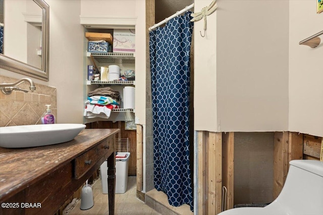 bathroom featuring walk in shower, toilet, sink, and decorative backsplash