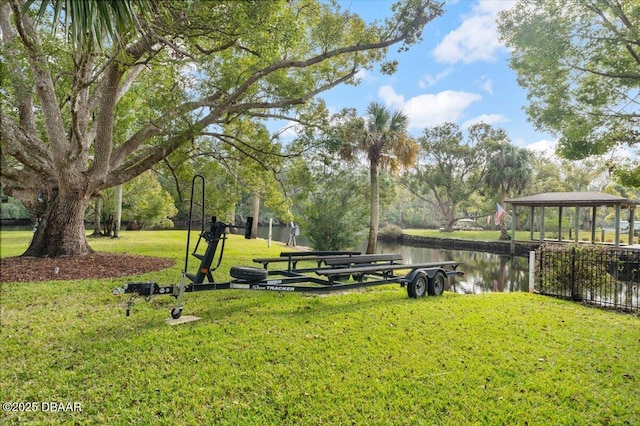 view of property's community with a water view and a lawn