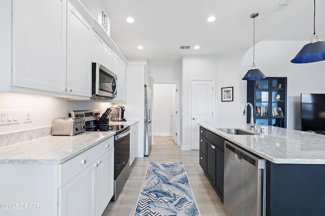 kitchen featuring appliances with stainless steel finishes, a center island with sink, a sink, and visible vents