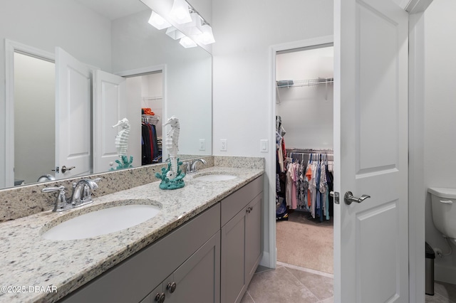 full bathroom with toilet, double vanity, a sink, and tile patterned floors