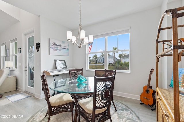 dining space with light wood finished floors, baseboards, and a chandelier