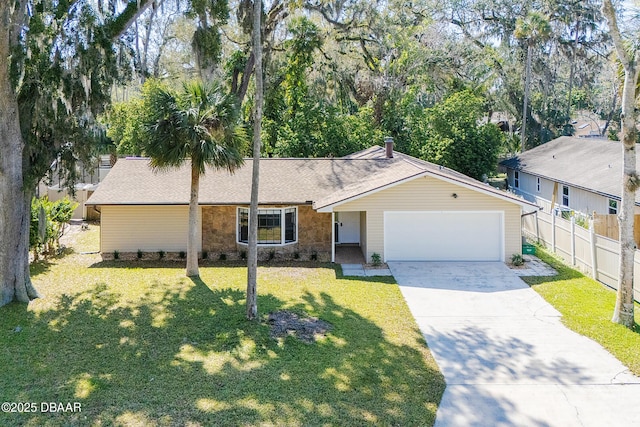 ranch-style house with driveway, stone siding, an attached garage, fence, and a front yard