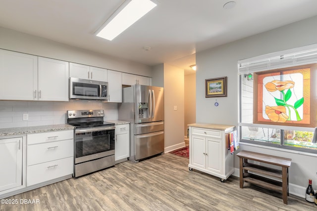 kitchen featuring tasteful backsplash, white cabinets, and stainless steel appliances