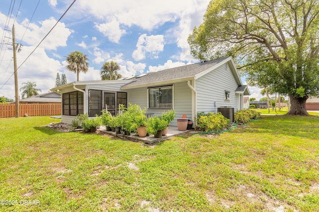 rear view of property with a lawn, cooling unit, and a sunroom