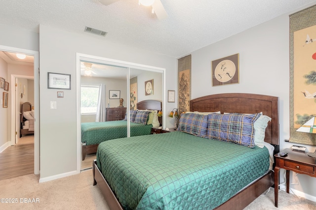 carpeted bedroom featuring a textured ceiling, a closet, and ceiling fan