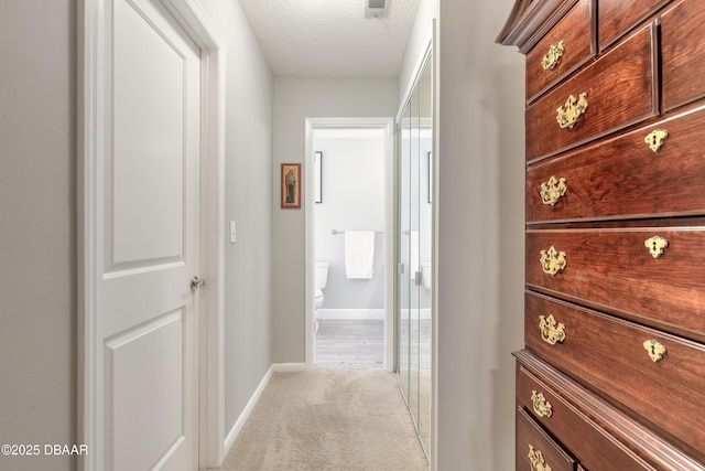 hallway featuring a textured ceiling and light colored carpet