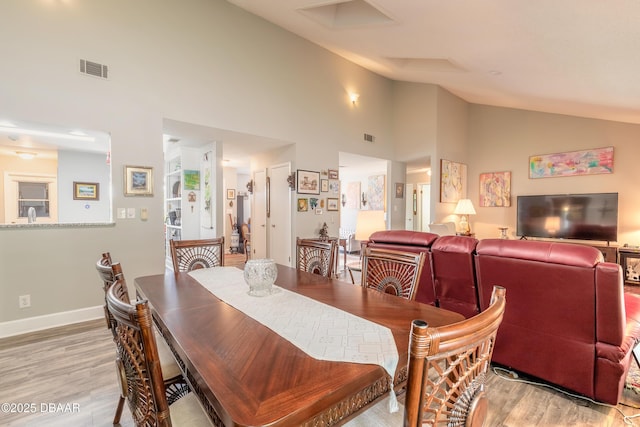 dining area featuring high vaulted ceiling and light hardwood / wood-style floors