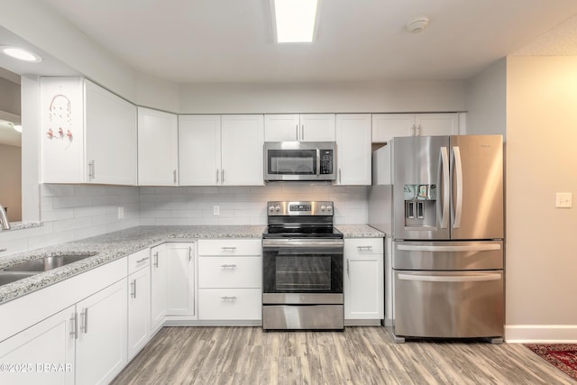 kitchen with appliances with stainless steel finishes, white cabinets, tasteful backsplash, and sink