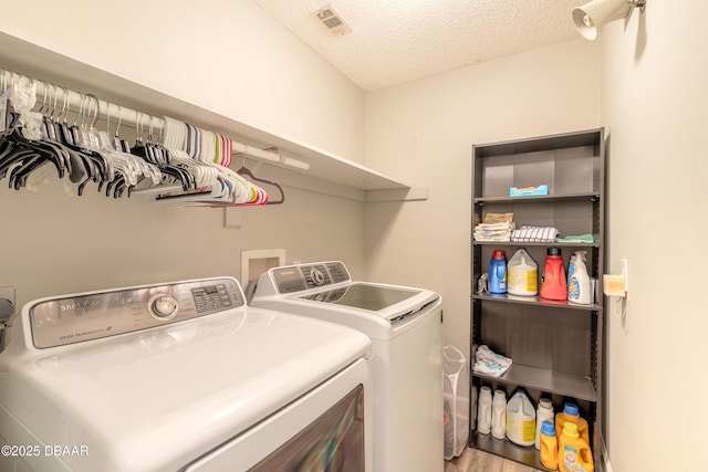 washroom with a textured ceiling, washer and dryer, and hardwood / wood-style floors