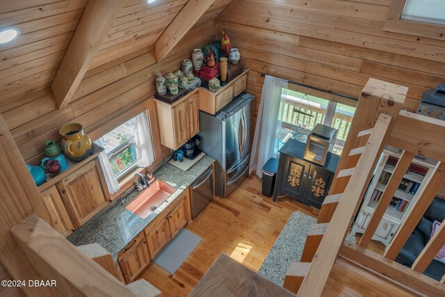 kitchen featuring light wood-type flooring, wood walls, and vaulted ceiling with beams