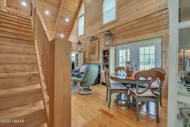 dining area with french doors, wood ceiling, hardwood / wood-style flooring, high vaulted ceiling, and a skylight