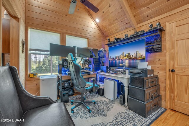 office featuring light hardwood / wood-style flooring, wood walls, vaulted ceiling with beams, and ceiling fan