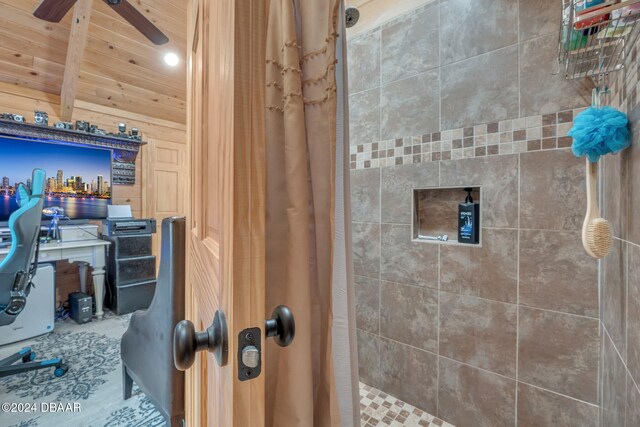 bathroom with ceiling fan, a shower with shower curtain, and vaulted ceiling with beams