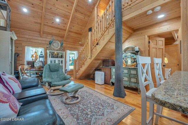 living room featuring wood walls, wood ceiling, vaulted ceiling with beams, and light hardwood / wood-style flooring