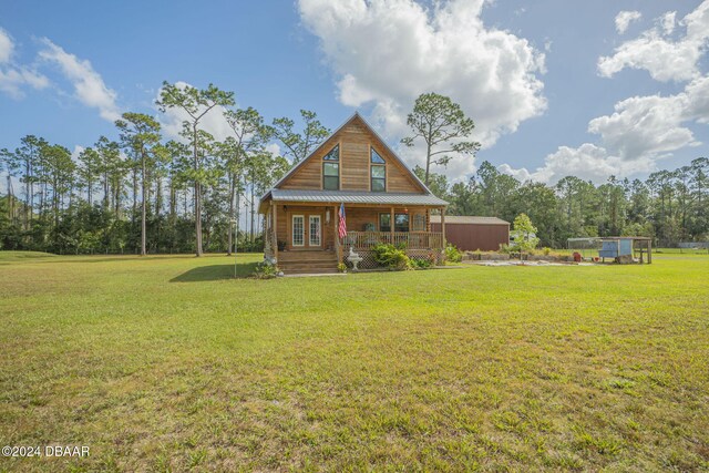 rear view of house featuring a yard and covered porch