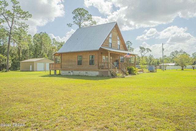 rear view of house with a yard, covered porch, and a storage unit