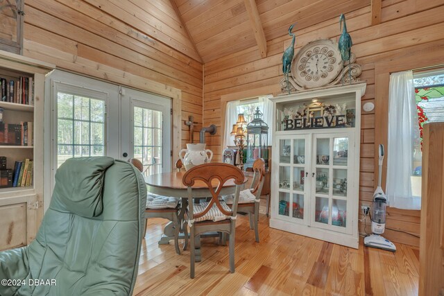 dining area with lofted ceiling with beams, french doors, light wood-type flooring, wood walls, and wooden ceiling