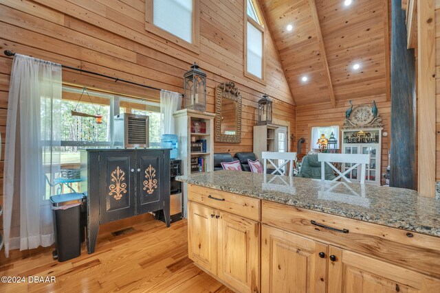 kitchen with light wood-type flooring, high vaulted ceiling, light brown cabinets, wooden walls, and wood ceiling