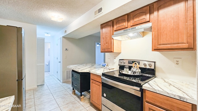 kitchen with light stone countertops, a textured ceiling, light tile patterned floors, and appliances with stainless steel finishes