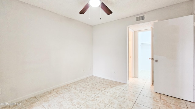 tiled empty room with ceiling fan and a textured ceiling