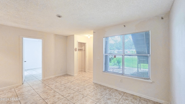 tiled spare room featuring a textured ceiling