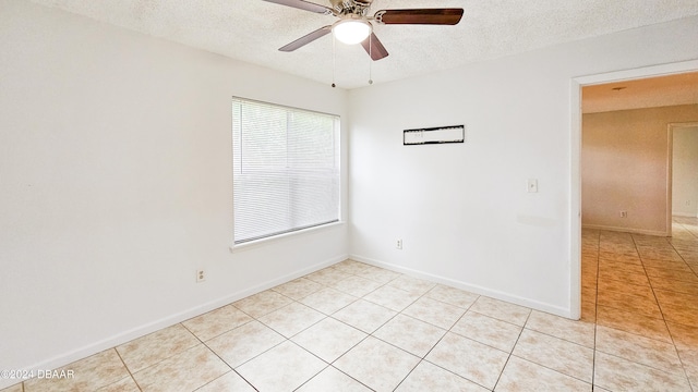 empty room featuring a textured ceiling, ceiling fan, and light tile patterned floors