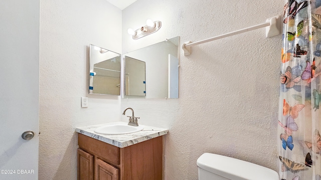 bathroom featuring curtained shower, vanity, and toilet