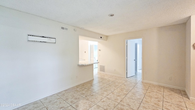 empty room featuring a textured ceiling and light tile patterned floors