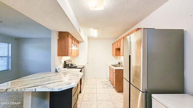 kitchen with sink, a textured ceiling, light tile patterned floors, and stainless steel appliances