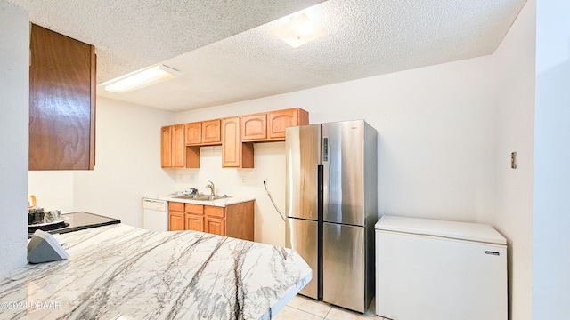 kitchen featuring a textured ceiling, stainless steel refrigerator, white dishwasher, fridge, and sink