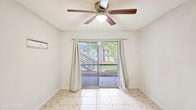 spare room featuring a textured ceiling, ceiling fan, and light tile patterned floors