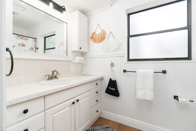 bathroom with hardwood / wood-style flooring, vanity, crown molding, and tasteful backsplash