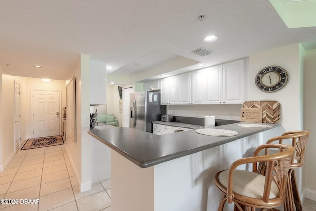 kitchen featuring stainless steel fridge with ice dispenser, a kitchen breakfast bar, kitchen peninsula, and white cabinets