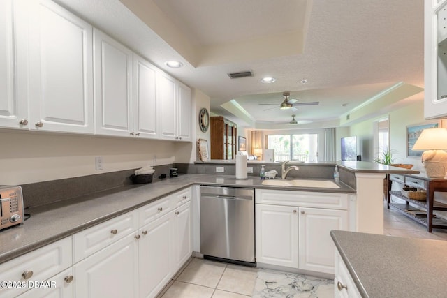 kitchen featuring a tray ceiling, white cabinetry, dishwasher, sink, and kitchen peninsula