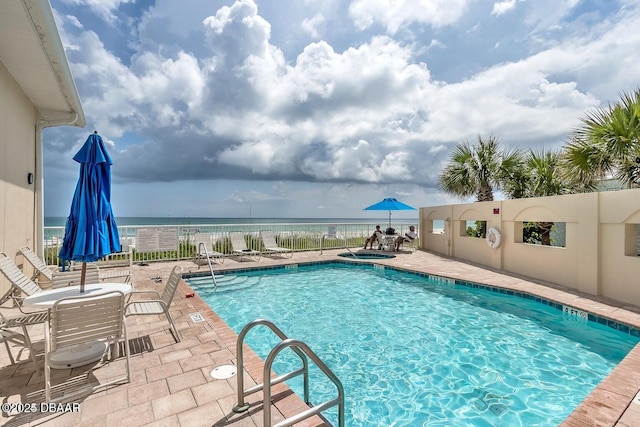 view of pool featuring a hot tub, a patio, and a water view