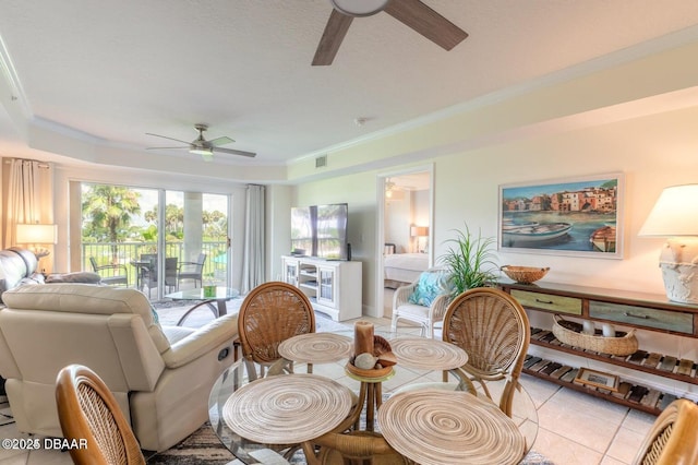 tiled dining area with ornamental molding, a raised ceiling, and ceiling fan