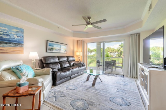 living room featuring ceiling fan, ornamental molding, a tray ceiling, and a textured ceiling