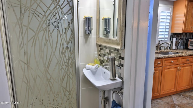 bathroom featuring decorative backsplash, a shower, and sink