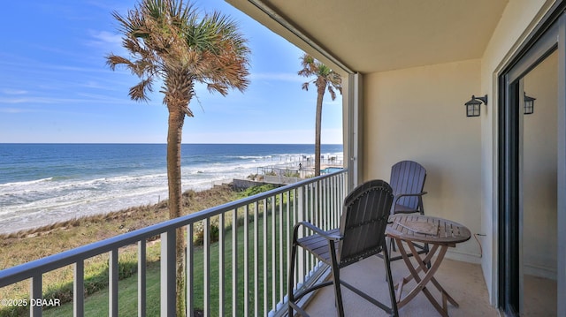 balcony featuring a water view and a beach view