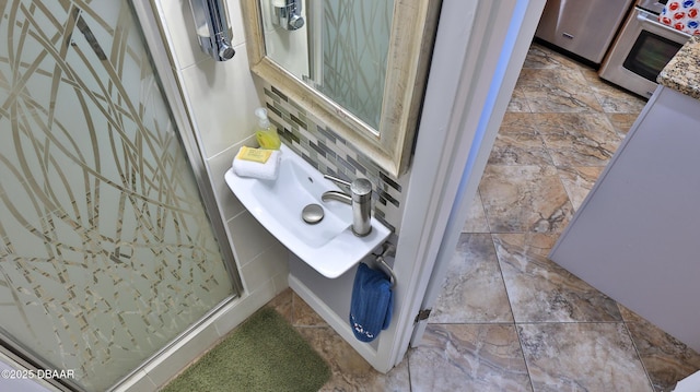 room details featuring decorative backsplash, stove, a shower with door, and sink