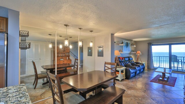 dining area with a textured ceiling and a water view