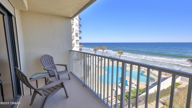 balcony with a water view and a view of the beach