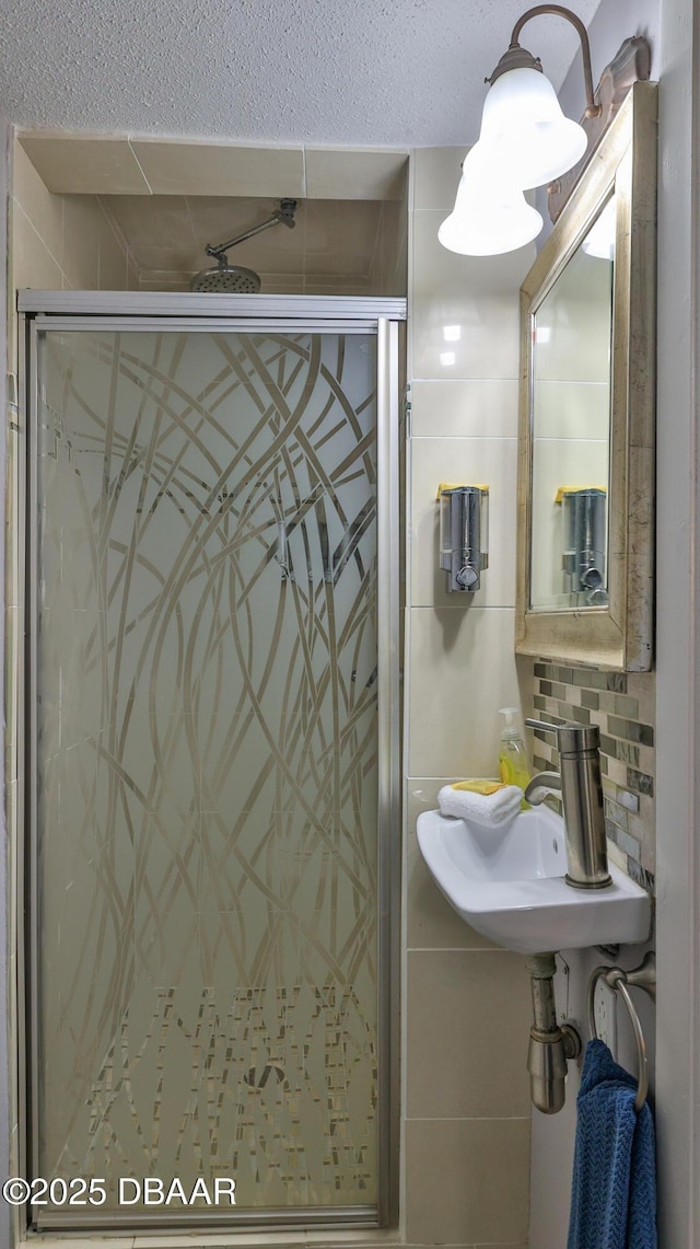 bathroom with a shower with door, sink, and tasteful backsplash