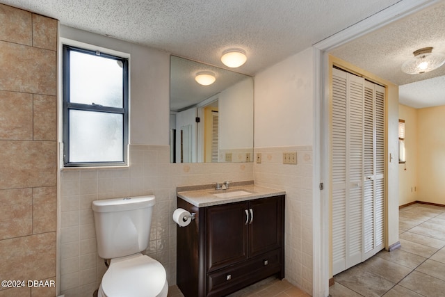 bathroom with a wealth of natural light, a textured ceiling, and tile walls