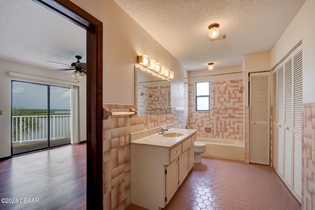 full bathroom with tile walls, vanity, and a textured ceiling