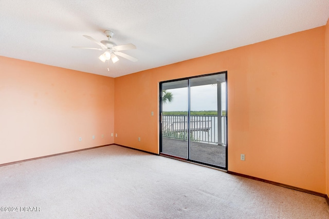 empty room featuring a water view, carpet flooring, and ceiling fan