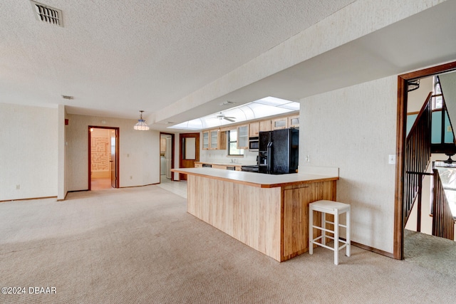 kitchen featuring black refrigerator with ice dispenser, light carpet, pendant lighting, and kitchen peninsula