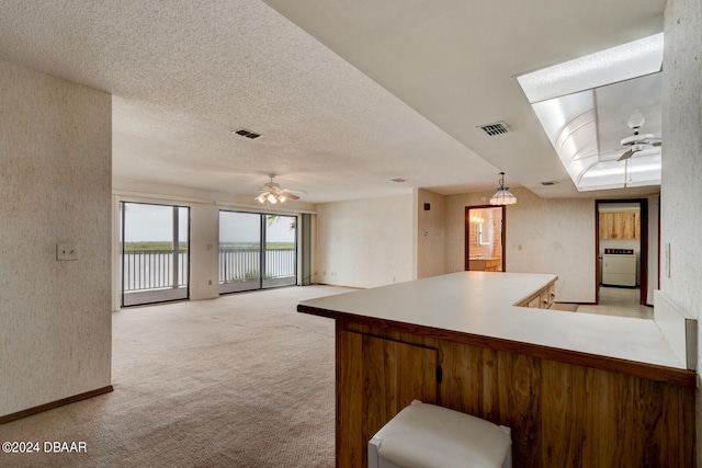 kitchen with ceiling fan, pendant lighting, kitchen peninsula, and light colored carpet